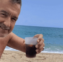 a man holding a plastic cup on the beach