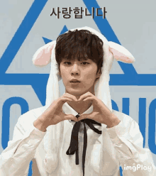 a young man wearing bunny ears makes a heart with his hands