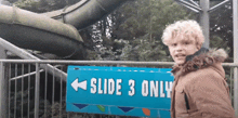 a young boy is standing in front of a slide that says slide 3 only