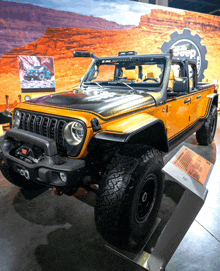 a yellow and black jeep is on display in front of a jeep sign