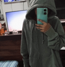 a person in a hoodie is taking a selfie with their cell phone