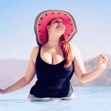 a woman in a black swimsuit and a watermelon hat is in the water