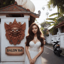 a woman in a white dress stands in front of a wall with a sign that says balon 168