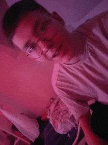 a young man wearing glasses is taking a selfie in a pink room