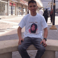 a man is sitting on a bench wearing a white t-shirt that says `` i love you pangga '' .