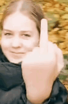 a woman is giving the middle finger in front of yellow leaves