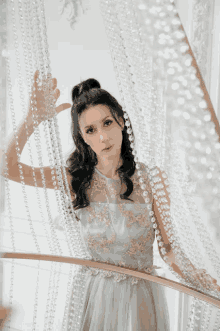 a woman in a light blue dress is standing in front of a chandelier