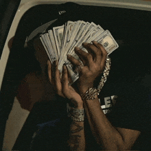 a man is holding a bunch of money in front of his face