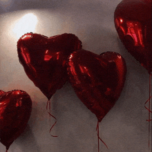 three red heart shaped balloons with red ribbons