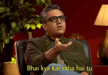 a man wearing glasses is sitting in a chair with the caption " bhai kya kar raha hai tu " on the bottom