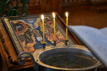 three candles are lit in front of a religious icon that says ' jesus ' on it