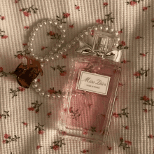 a bottle of miss dior perfume sits on a flowered cloth