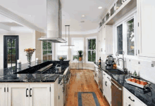 a kitchen with black counter tops and white cabinets and stainless steel appliances