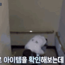 a person is crawling down a set of stairs in a room with korean writing on the wall