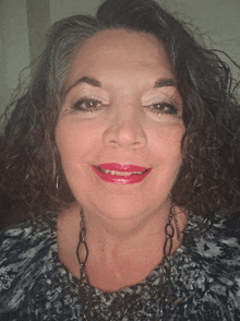 a woman with curly hair wearing red lipstick and a necklace