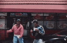 two men are dancing in front of a restaurant with a sign that says ' the best in town '