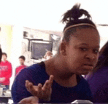 a woman in a blue shirt is sitting at a table with her hand out