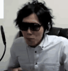 a man wearing headphones and sunglasses is sitting in a chair .