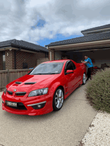 a man stands next to a red car with a license plate that says 580 hsv