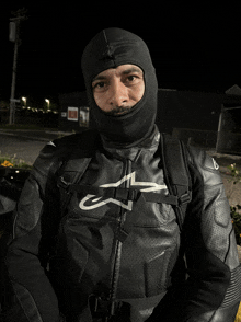 a man wearing a black alpinestars jacket and a black mask