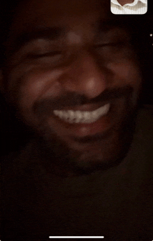 a man with a beard is smiling during a video call on his phone