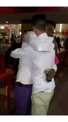 a man hugging another man in front of a sign that says infiniti