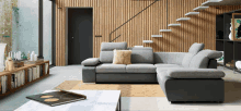 a living room with a gray sectional couch and stairs in the background