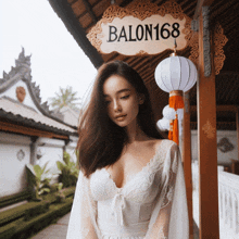 a woman in a white dress stands under a sign that says balon168