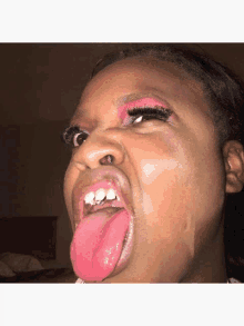 a woman with pink makeup on her face sticks out her tongue