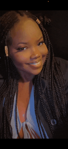 a woman with braids is smiling and wearing a blue top