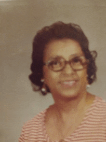 a woman wearing glasses and a striped shirt is smiling