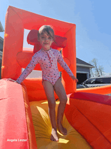 a little girl in a pink bathing suit is playing on a bouncy house