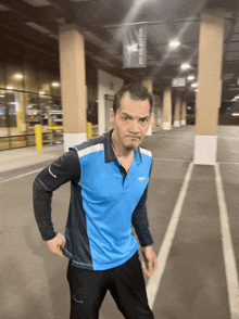 a man in a blue amazon shirt stands in a parking garage