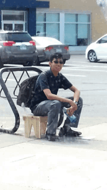 a man sits on a stool with a bottle of water