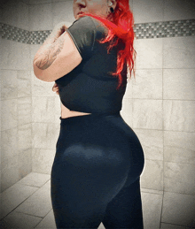 a woman with red hair is wearing black pants and a black top