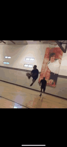 a man is jumping in the air while playing basketball in front of a poster of a man holding a basketball