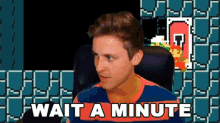 a man is sitting in front of a video game screen and says wait a minute .