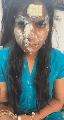 a girl with cake on her face and a square on her forehead