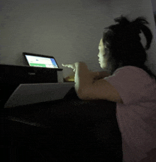 a woman in a pink shirt is looking at a laptop screen