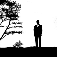 a silhouette of a man in a suit and tie standing next to a tree