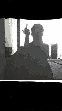 a man is giving the middle finger in front of a window