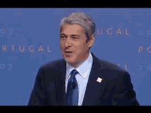 two men are standing at podiums in front of a crowd and the words lisbon are on the wall behind them