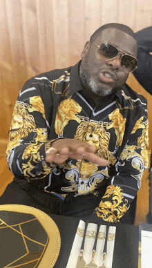 a man sitting at a table wearing a shirt with a lion design