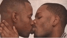 two men are kissing each other with their eyes closed .