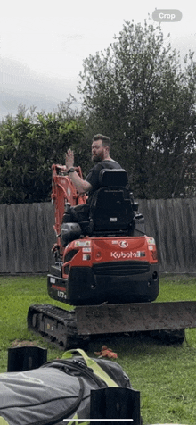 a man sitting on a kubota bulldozer in a yard