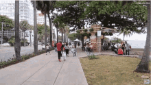 a group of people are walking down a sidewalk in front of a sign that says ' coca cola '