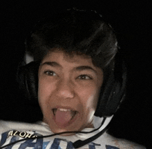 a young boy is wearing headphones and sticking his tongue out .