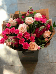 a bouquet of pink roses and carnations in a black bag with the word fleurs on it