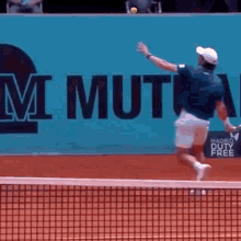 a man is playing tennis on a court with a sign that says madrid duty free in the background .