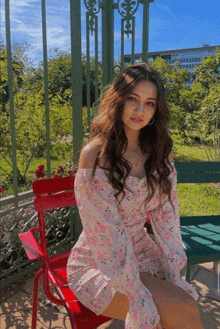 a woman in a pink dress sits on a red chair